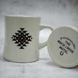 The Brown Out Yonder Mug Next To The Design On The Bottom Of The Mug